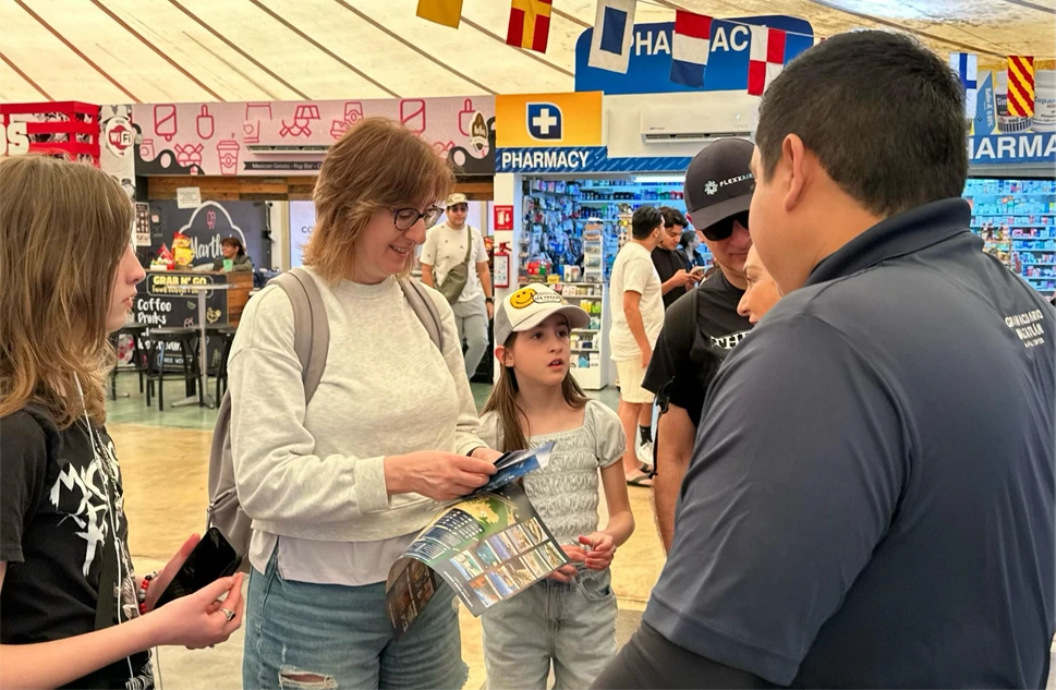 Un integrante del Gran Acuario Mazatlán entrega un folleto a una familia de cruceristas